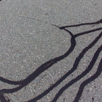 A road with cracks that have been sealed with tar.