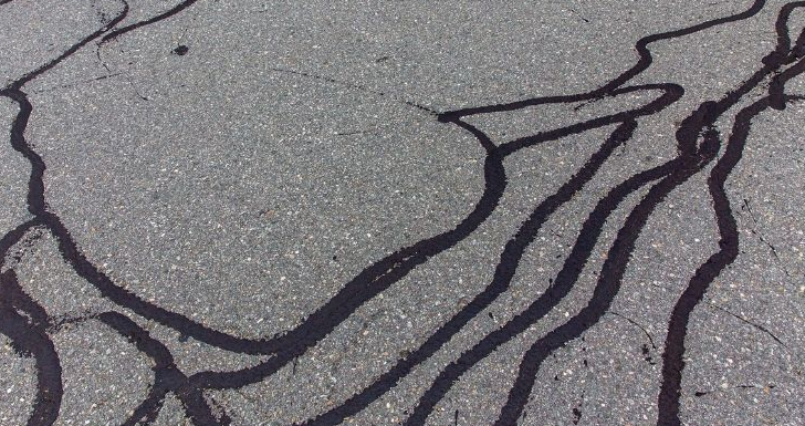 A road with cracks that have been sealed with tar.